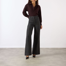 Model wearing Victoria Beckham Alina High-Rise Wide Leg Trousers in Ore Melange, styled with a dark burgundy shirt and black heels.