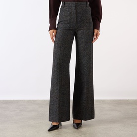 Model wearing Victoria Beckham Alina High-Rise Wide Leg Trousers in Ore Melange, wide-cut pressed creases, styled with black heels and burgundy top.