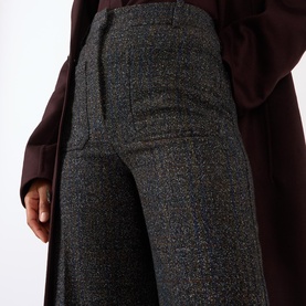 Model wearing Victoria Beckham Alina High-Rise Wide Leg Trousers in Ore Melange, wide-cut legs with pressed creases, styled with a burgundy coat.