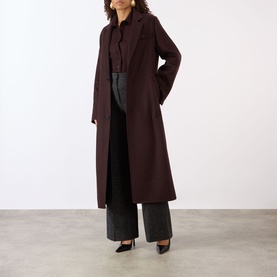 Model wearing Victoria Beckham Alina High-Rise Wide Leg Trousers in Ore Melange, styled with a burgundy longline coat and black heels.