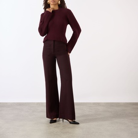 Model wearing Victoria Beckham Alina High-Rise Wide Leg Trousers in Acai, styled with a ribbed knit sweater and black heels.