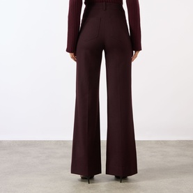 Model wearing Victoria Beckham Alina High-Rise Wide Leg Trousers in Acai, wide-cut legs with pressed creases, styled with a ribbed top.