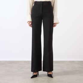 Model wearing Victoria Beckham black wide-leg tailored trousers with high waist, styled with black pointed-toe heels and cream blouse.