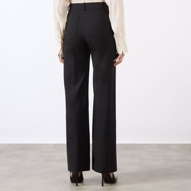 Model wearing Victoria Beckham black wide-leg trousers, rear view, styled with a cream blouse and black heels.