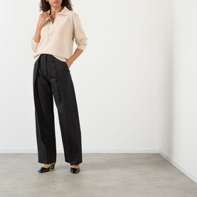Model wearing Victoria Beckham Dark Grey Melange wide-leg trousers with pleat detail, styled with a cream polo top and black heels.