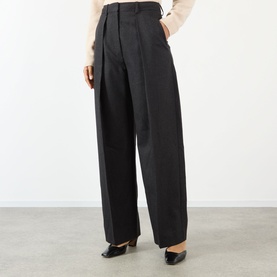 Model wearing Victoria Beckham dark grey melange wide-leg pleated trousers, styled with a cream knit top and black heeled shoes.
