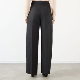Model wearing Victoria Beckham trousers in Dark Grey Melange, wide-leg cut with pressed crease, shown from behind, styled with a cream top.