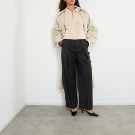 Model wearing Victoria Beckham Dark Grey Melange wide-leg trousers, styled with a beige blouse, trench coat and black heels.