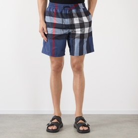 Model wearing Burberry carbon blue IP check swim shorts, styled with black strappy sandals