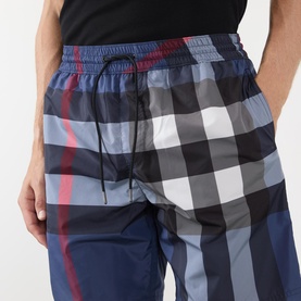 Model wearing Burberry swim shorts in carbon blue IP check, with elasticated drawstring waist and signature oversized check print.