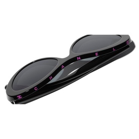Chanel black oval sunglasses, overhead view showing CHANEL lettering in pink on the bridge and dark lenses