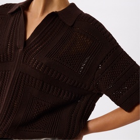 Model wearing Whistles brown crochet-knit polo top with open-stitch pattern, short sleeves, and V-neck collar detail