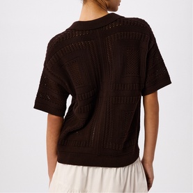 Model wearing Whistles brown open-knit short-sleeve sweater, back view, styled with white wide-leg trousers.