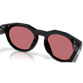 Oakley sunglasses in black with round frames and rose-tinted lenses, angled product view