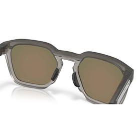Oakley sunglasses with translucent grey square frames and gold-toned mirrored lenses, angled three-quarter view
