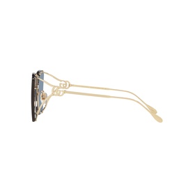 Gucci sunglasses in gold, side profile view showing ornate gold filigree frame detailing and slim temple arms with blue lenses.