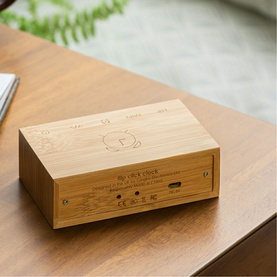 Gingko bamboo wooden alarm clock with engraved top panel and USB port, placed on a wooden desk surface