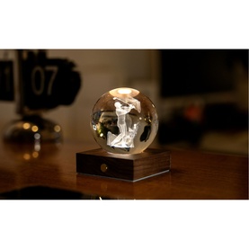 Gingko crystal ball lamp with engraved golfer figure, illuminated warm glow, on dark wood rectangular base, styled on wooden desk