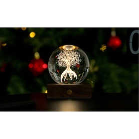 Gingko illuminated crystal ball light with engraved tree and deer design on wooden base, glowing warm white, styled near a Christmas tree