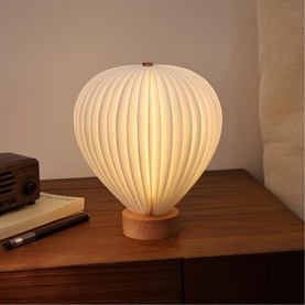 Gingko ribbed balloon-shaped table lamp with warm white diffuser shade and natural wood base, styled on a wooden bedside table