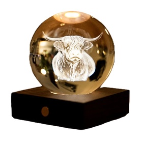 Gingko crystal ball light with 3D engraved highland cow design, warm LED glow, on a dark wooden USB base