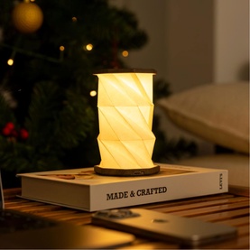 Gingko Mini Walnut Drift light glowing warm amber, placed on a book, styled in a cosy festive home setting