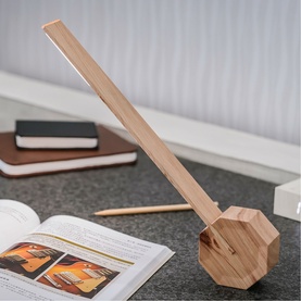 Gingko octagonal wooden desk lamp with angled slim bar arm, shown on a desk beside an open book and stacked notebooks