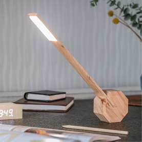 Gingko desk lamp in natural wood finish with octagonal base and adjustable illuminated arm, styled on a desk with clock and pencils