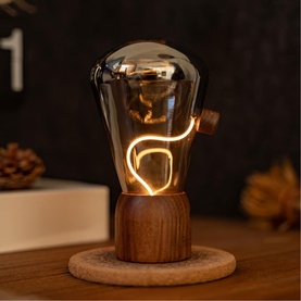 Gingko decorative LED bulb lamp with smoked glass shade and warm glowing filament, on a round wooden base