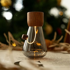 Gingko smoked glass teardrop light with walnut wood cap, glowing warmly, styled on a festive table with bokeh Christmas tree background