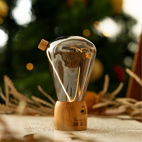 Decorative LED Edison-style bulb lamp with smoked glass and warm wooden base, styled against a festive Christmas tree backdrop