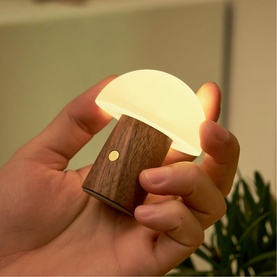 Handheld mushroom-shaped mini lamp with warm white glow, dark walnut wood base and frosted silicone cap with gold button detail