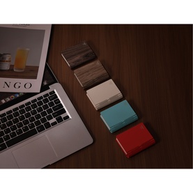 Gingko Coral Red light shown alongside walnut, stone and teal variants on a wooden desk next to a laptop