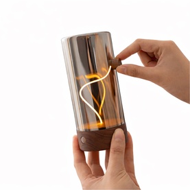 Gingko portable lamp with warm amber LED filament in smoked glass and walnut base, shown being switched on by hand