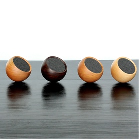 Gingko Mini Speaker set of four in light and dark wood tones with black mesh fronts, displayed on dark surface