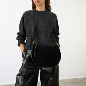 Model carrying Isabel Marant Bruine Soft Zip Crossbody Bag in black suede with braided trim, gold hardware, styled with dark knit and leather