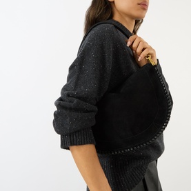 Model carrying Isabel Marant Bruine Soft Zip Crossbody Bag in black suede with braided trim and brass-toned hardware, styled with dark knit jumper
