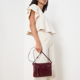 Model carrying Isabel Marant Winna Duo Shoulder Bag in burgundy glossy leather with silver-tone hardware, styled with cream co-ord set