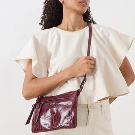 Model carrying Isabel Marant Winna Duo Shoulder Bag in burgundy glossy leather, silver-tone hardware, worn as crossbody with adjustable strap