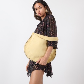 Model carrying Isabel Marant Oksan Hobo Shoulder Bag in straw, with silver-tone stud trim detail. Styled with a dark floral mini dress.