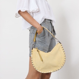 Model carrying Isabel Marant Oksan Zip Shoulder Bag in straw, silver-tone studs around trim, top zip fastening, worn with denim shorts