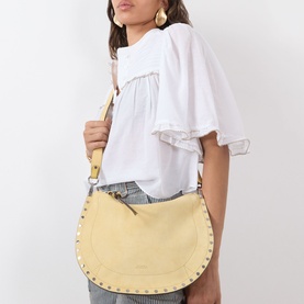 Model carrying Isabel Marant Oksan Zip Shoulder Bag in straw suede with silver-tone stud trim and tan crossbody strap, styled with white top and jeans