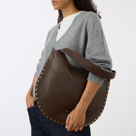 Model carrying Isabel Marant Oksan Hobo Shoulder Bag in coffee grained leather with gold-tone stud trim detailing, styled with grey cardigan and
