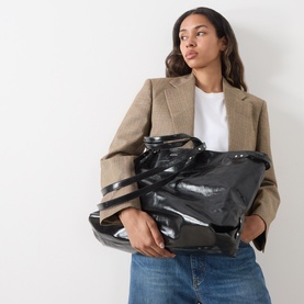 Model carrying Isabel Marant Winna Tote Bag in black patent leather, slouchy silhouette with silver-tone hardware, styled with camel blazer and jeans