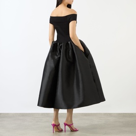 Model wearing Marques Almeida Mikado Princess Dress in black, off-shoulder bodice, full midi puff skirt with pockets, styled with pink heels.