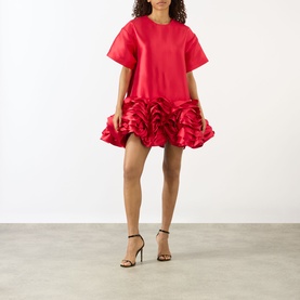 Model wearing Marques Almeida red mini dress with ruffled hem and short sleeves, styled with black strappy heeled sandals.