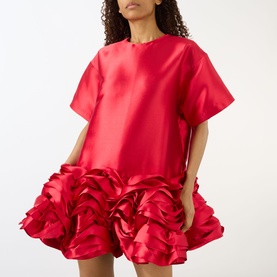 Model wearing Marques Almeida red short-sleeve mini dress with voluminous 3D floral ruffle hem detail in satin finish.
