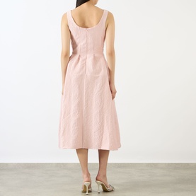 Model wearing Marques Almeida Pink Textured Brocade Dress, sleeveless midi length, pleated skirt, shown from behind with gold heeled mules.