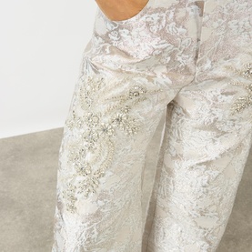Model wearing Marques Almeida white jacquard jeans with floral beaded and crystal embellishments, close-up detail shot.