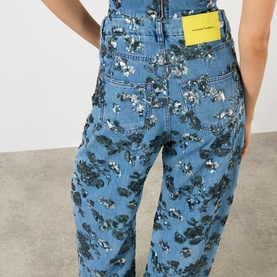 Model wearing Marques Almeida Sequin Embroidered Boyfriend Jeans in mid blue denim with floral sequin embroidery, rear view showing logo patch.